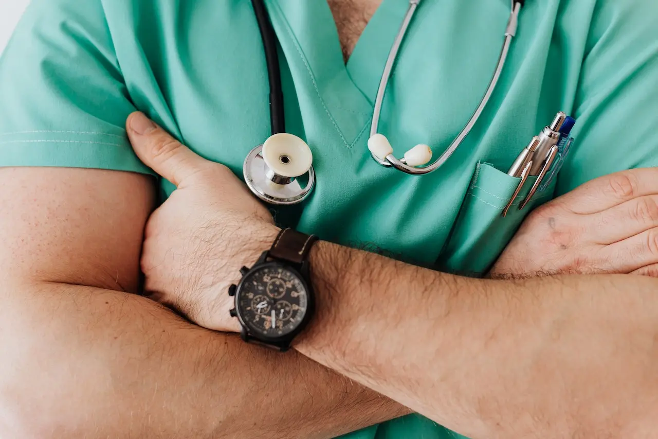 Healthcare provider in green scrubs holding stethoscope and wearing watch
