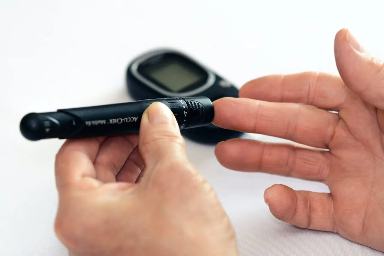 Person holding a blood glucose meter and lancing device for diabetes testing